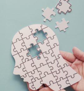 Hands holding brain with puzzle paper cutout, autism, memory loss, dementia and alzheimer awareness, world mental health day concept